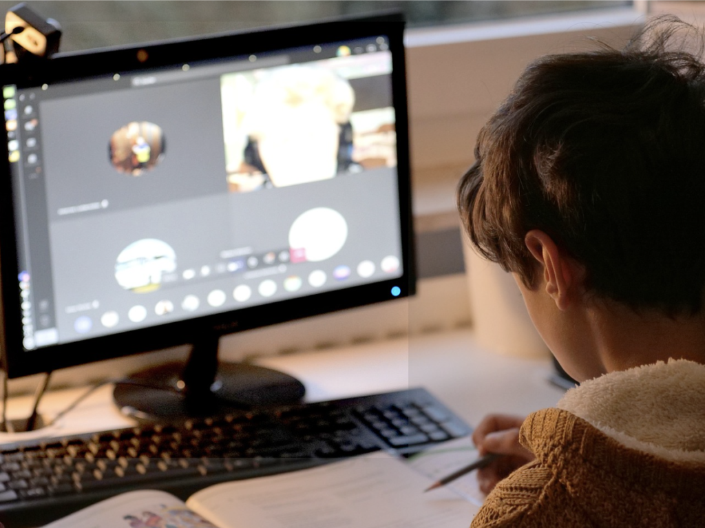 enfant avec crayon dans la main et devant un ordinateur