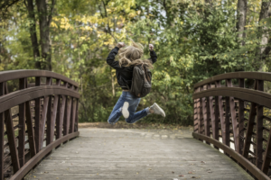 enfant sur un pont qui saute en l'air et brandit ses bras de victoire