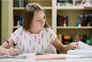 fille en train de prendre des notes d'un livre pour réviser