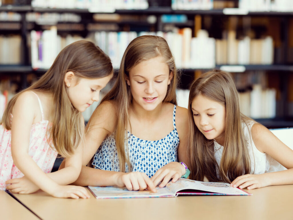 trois filles occupées à lire un même livre