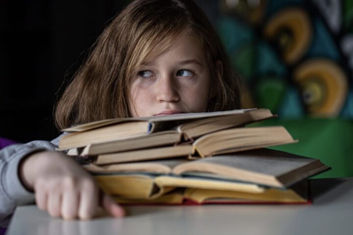 Jeune fille cachée devant une grosse pile de livres
