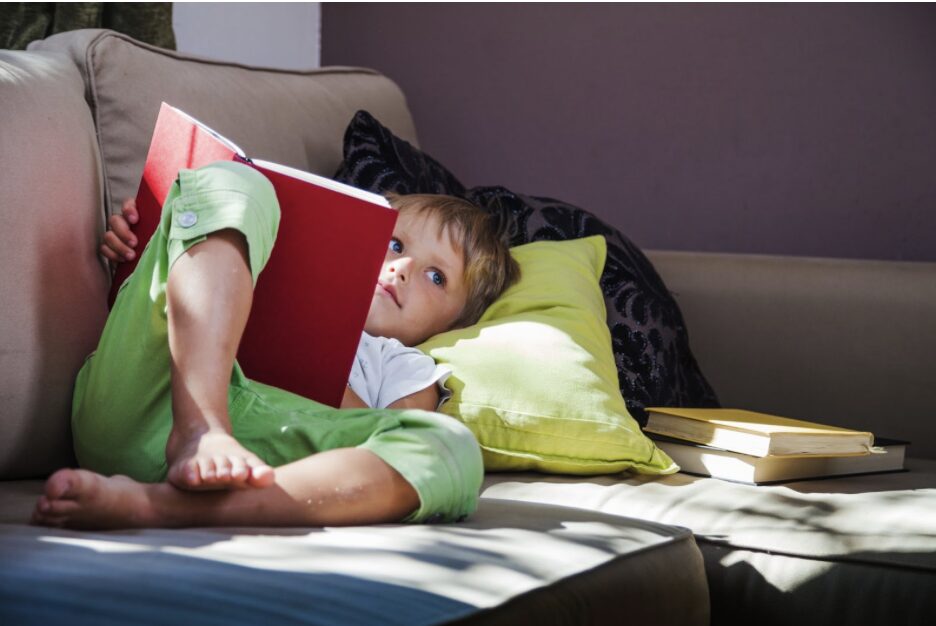 enfant allongé sur un canapé avec un livre
