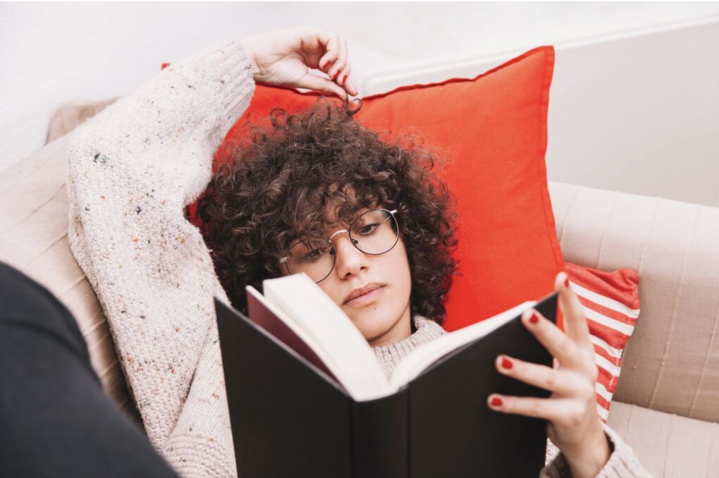 Jeune adulte lisant un livre sur un canapé