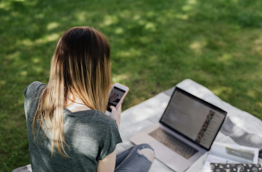 jeune femme assise sur l'herbe en regardant son smartphone