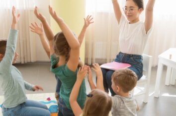 enseignant qui chante une comptine avec des gestes à plusieurs enfants
