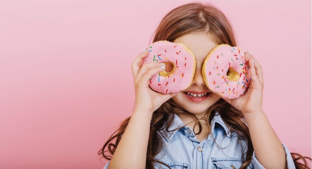 jeune fille avec deux donuts dans les mains qu'elle place devant les yeux