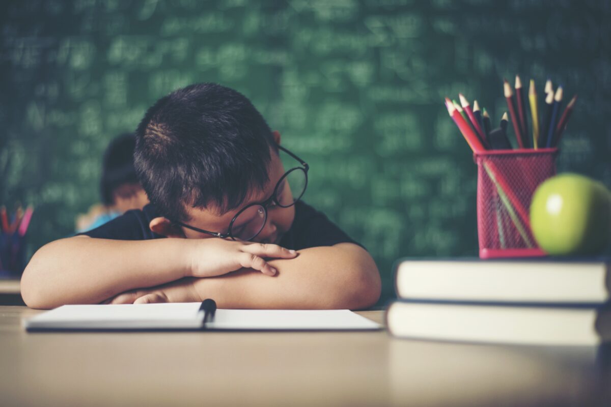 Enfant en train de dormir sur sa table en classe