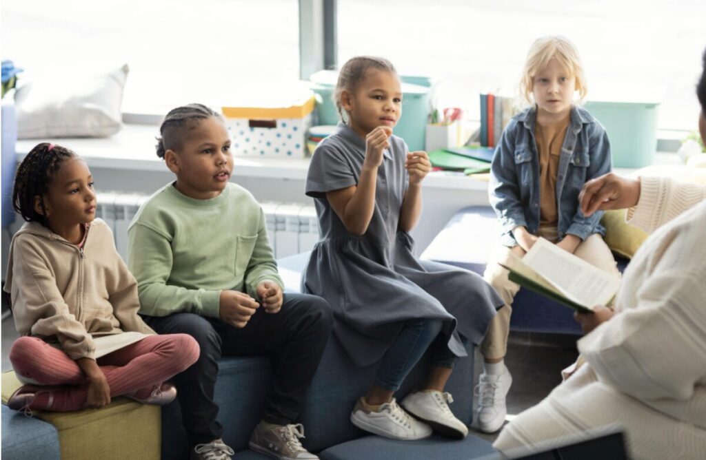 enfants assis sur un banc en classe en train d'écouter une personne