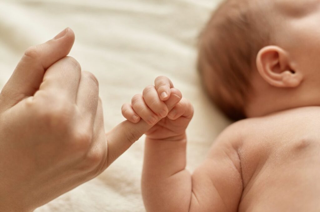 Nourrisson en train de tenir le doigt de sa maman