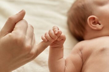 Nourrisson en train de tenir le doigt de sa maman