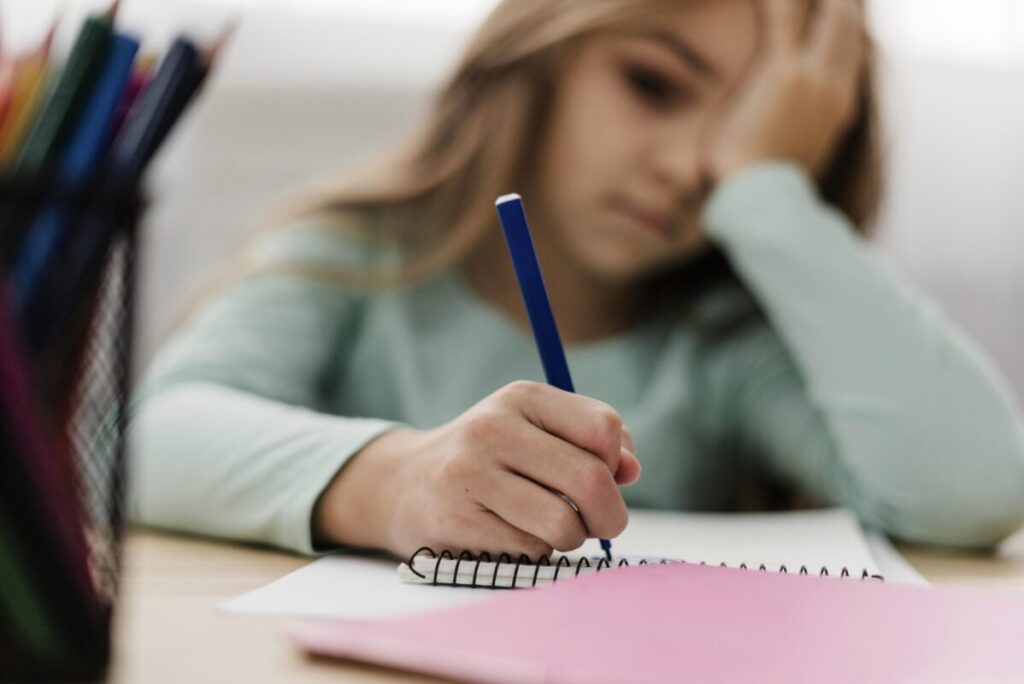 Jeune fille démotivée en train d'écrire sur un cahier