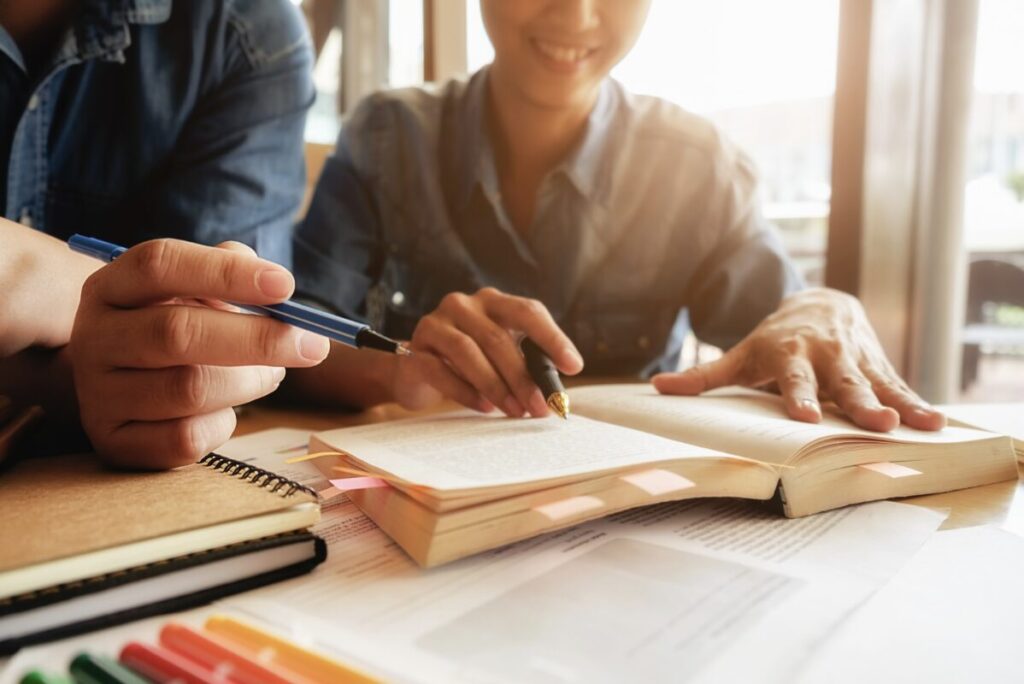 Elève en train de travailler devant un livre avec un enseignant qui l'accompagne