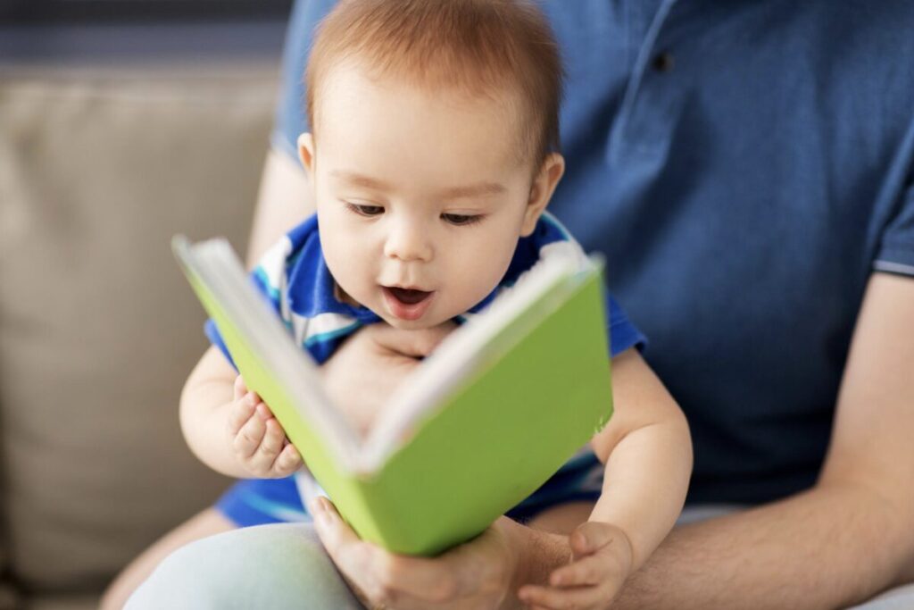 Très jeune enfant en train de regarder un livre sur les genoux de son parent avec beaucoup de curiosité