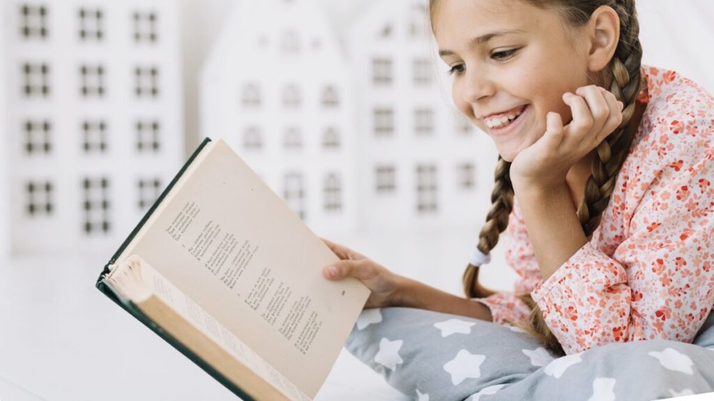 Jeune fille allongére sur un canapé en train de lire un livre avec beaucoup d'intérêt et de joie