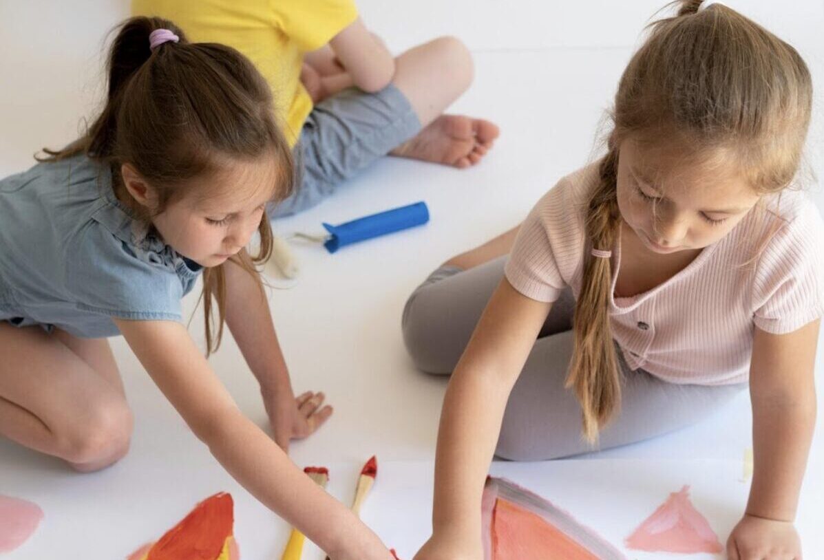 trois enfants en train de faire de la peinture en autonomie sans adulte avec eux