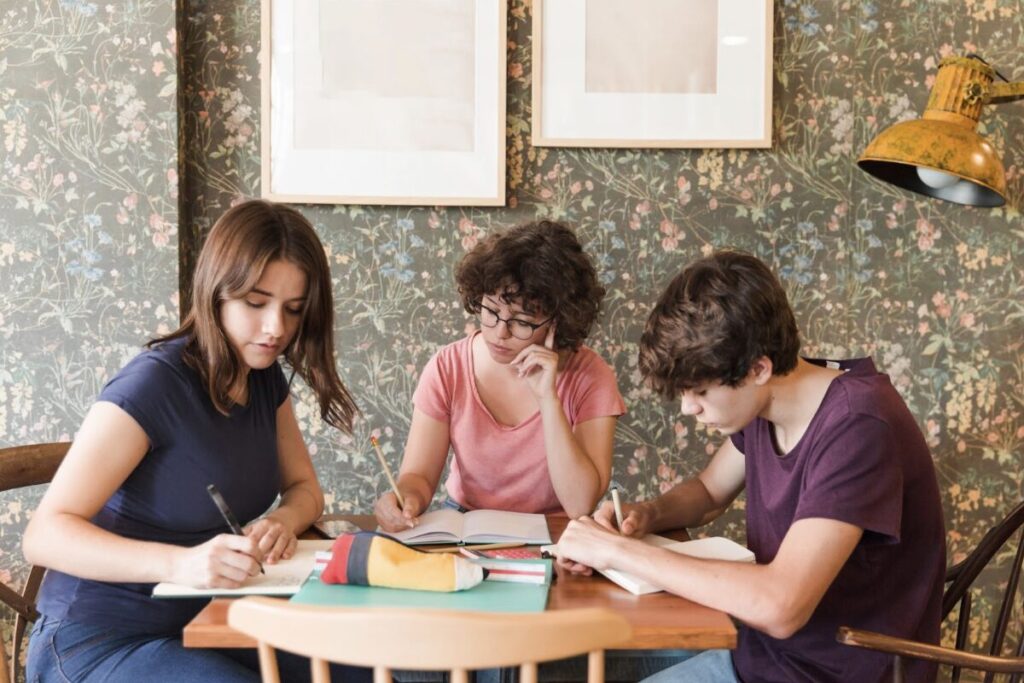 Trois jeunes en train de travailler à une table en autonomie collaborative