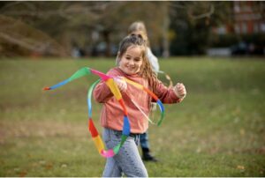 Une jeune fille joue dans l'herbe avec un ruban coloré