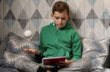 Jeune garçon dans sa chambre en train de faire son travail scolaire et de lancer en même temps avec une main une balle, bénéfice du rythme