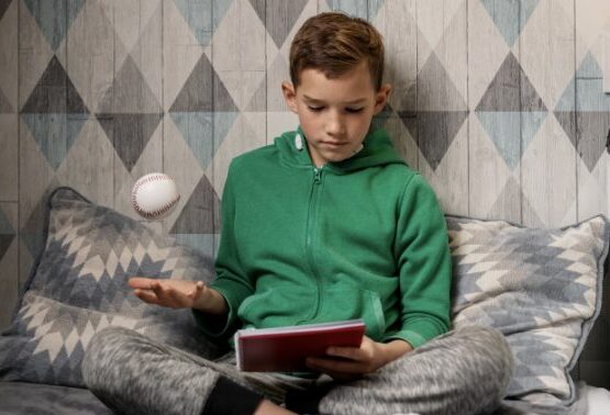 Jeune garçon dans sa chambre en train de faire son travail scolaire et de lancer en même temps avec une main une balle, bénéfice du rythme