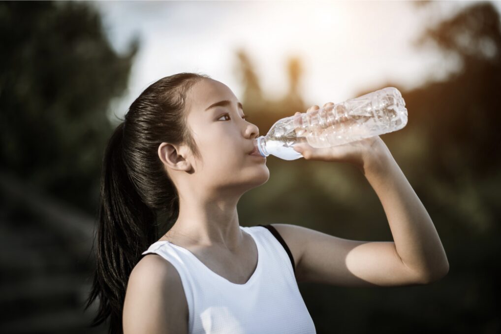 Jeune fille en train de boire de l'eau pour s'hydrater et donner à son cerveau l'énergie dont il a besoin pour travailler efficacement
