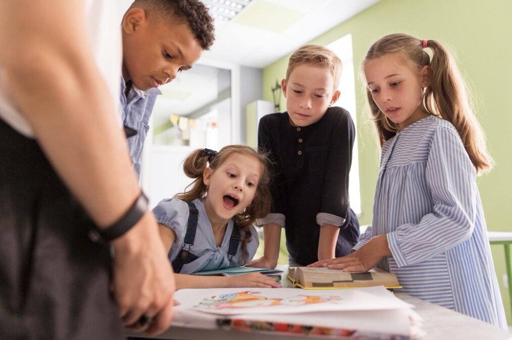 Jeunes enfants rassemblés autour d'un travail scolaire en train de l'évaluer avec attention