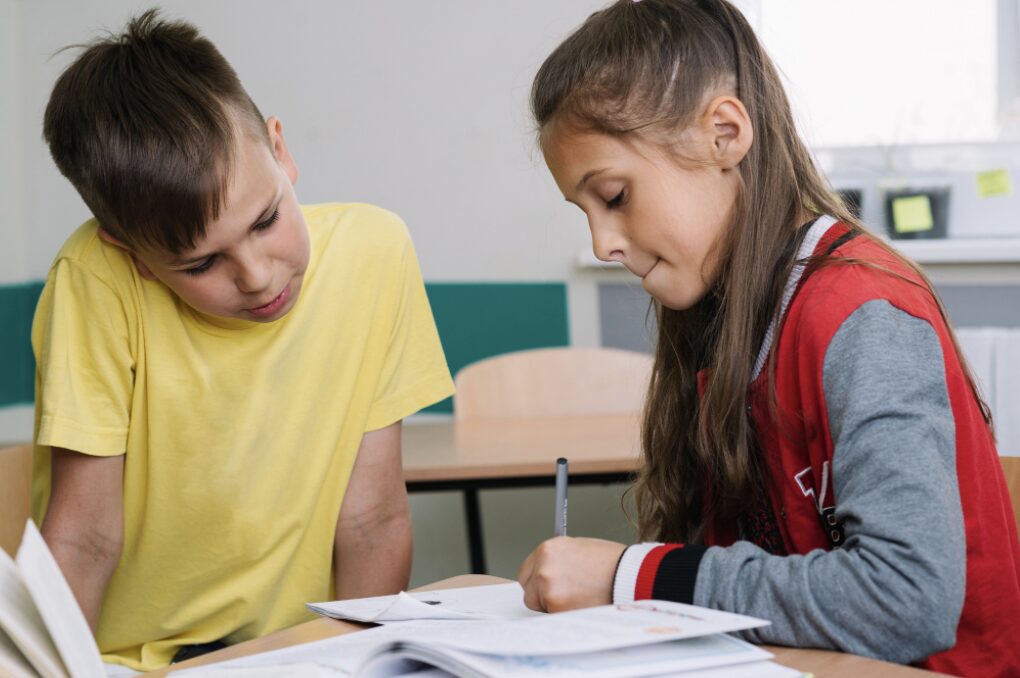 Deux élèves dans leur classe d'école en train de corriger les erreurs d'orthographe